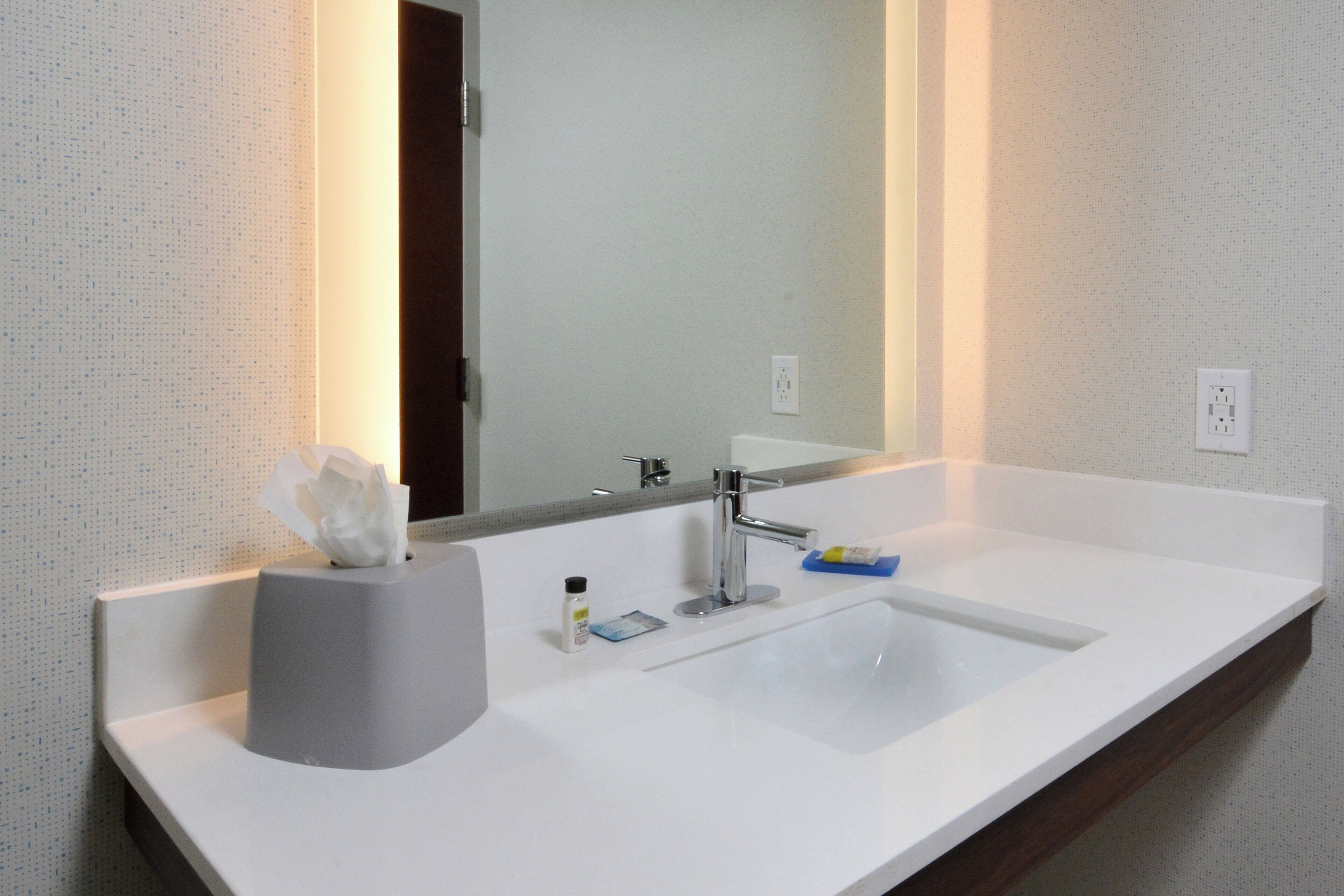 A bathroom with a white sink, a mirror, and a tissue holder.