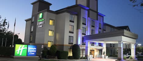 A Holiday Inn Express & Suites hotel with a modern design, featuring a large signboard and a well-lit entrance.