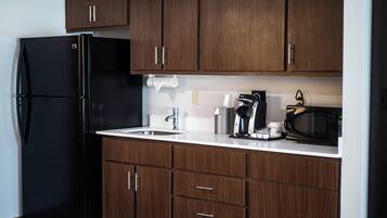 A kitchen with dark wood cabinets, a black refrigerator, a coffee maker, and a microwave.
