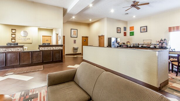 A hotel lobby with a reception desk, seating area, and a kitchenette.
