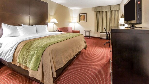 A hotel room with a large bed, a desk with a computer, a television, and a window with curtains. - Quality Inn & Suites Portsmouth (Portsmouth)
