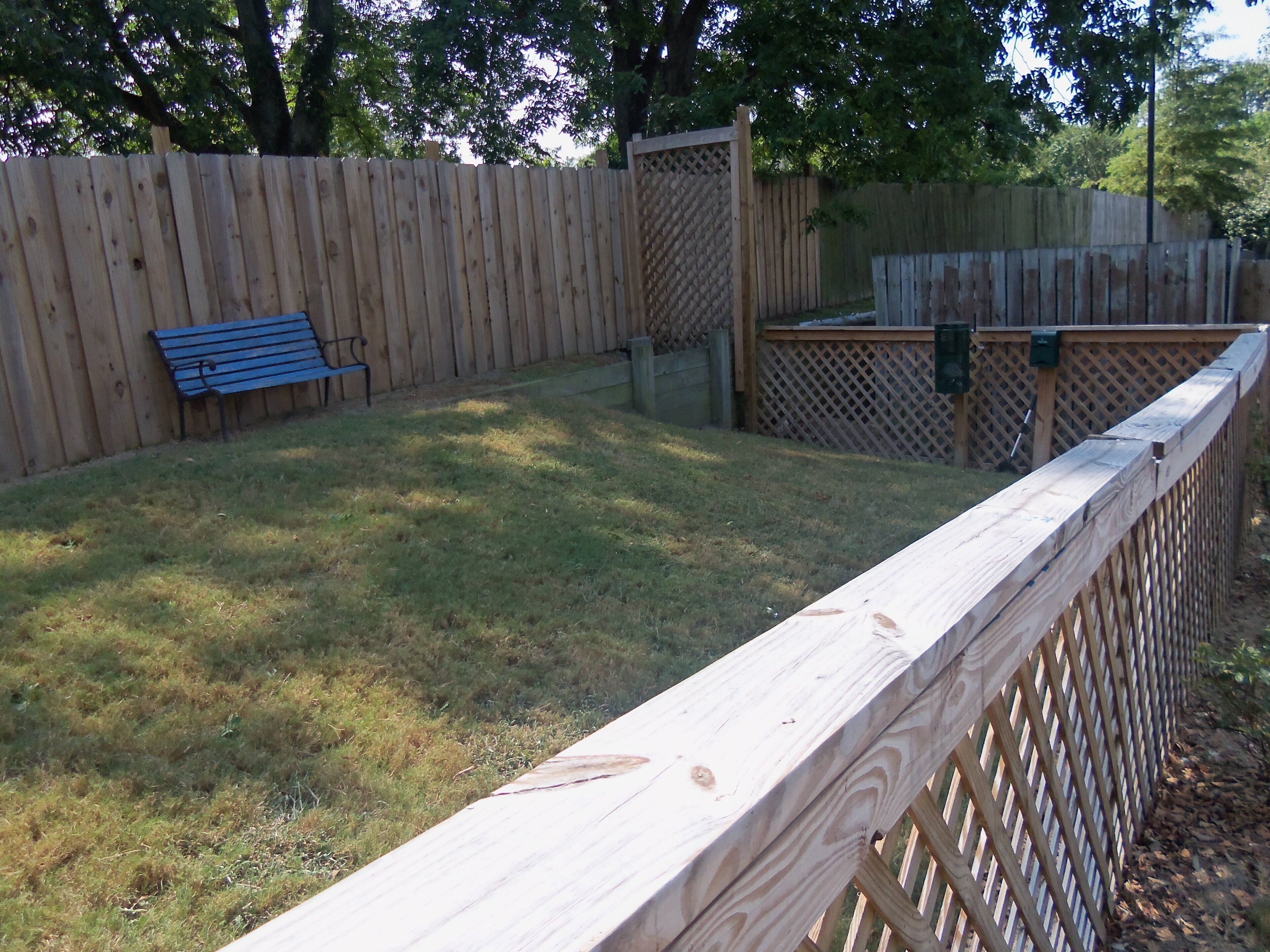 Une cour arrière clôturée avec un banc en bois et une clôture en bois.