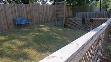 Une cour arrière clôturée avec un banc en bois et une clôture en bois.