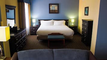 Une chambre d’hôtel avec un grand lit, deux tables de chevet, une commode, un banc et un miroir.
