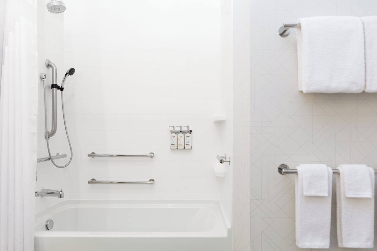 Une salle de bain moderne équipée d’une baignoire, d’une douche et d’un porte-serviettes.