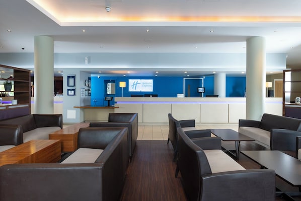 Un moderno vestíbulo de hotel con un mostrador de recepción, zona de estar y una pared de acento azul.
