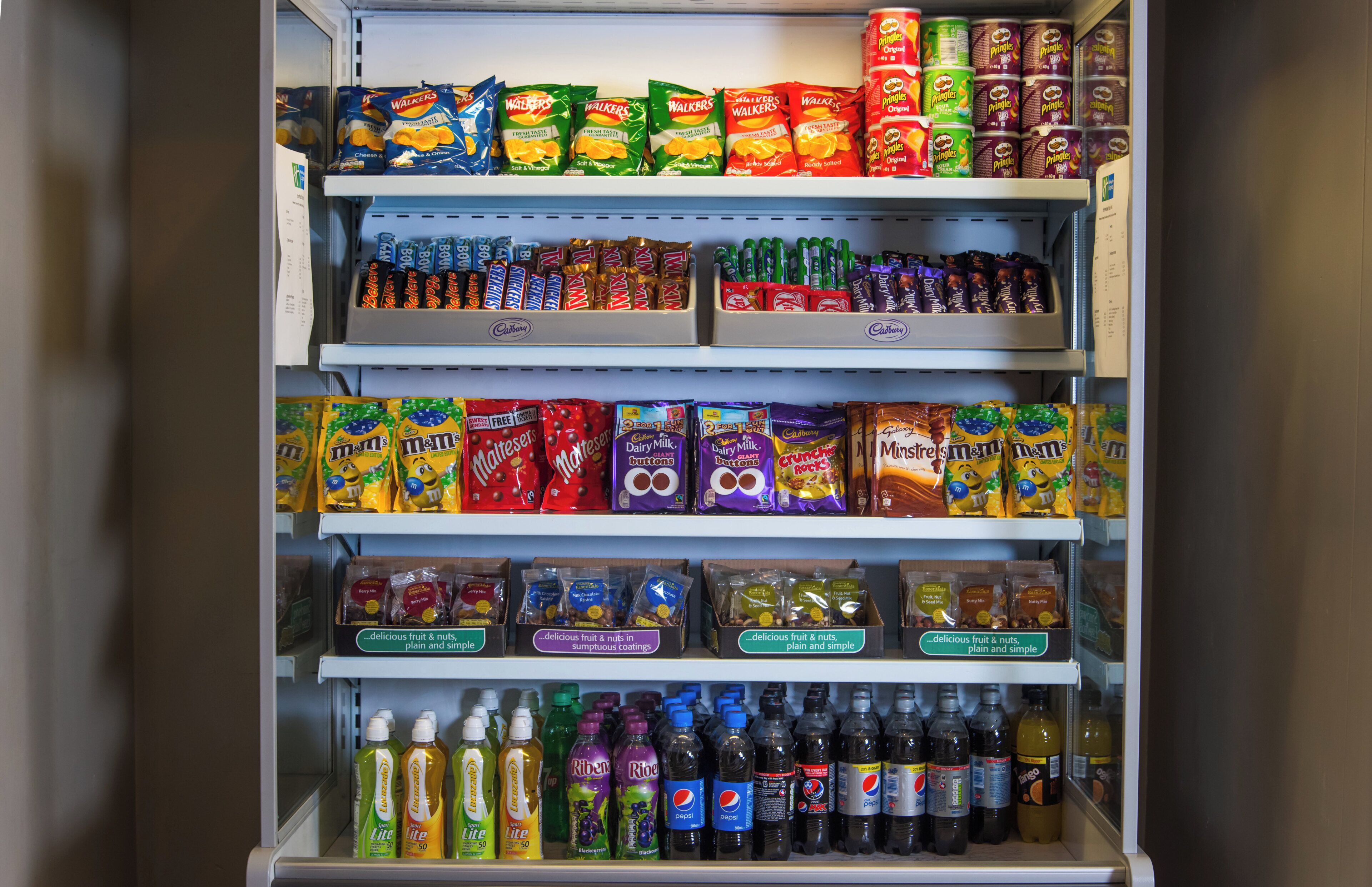 A refrigerated display case with various snacks, chocolates, and beverages.