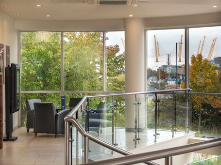 A modern interior with large windows, a staircase, and a view of construction cranes outside.