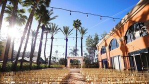 An outdoor wedding venue with rows of chairs and a floral archway.