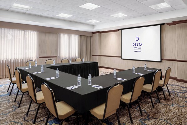 A conference room with a long table, chairs, water bottles, and a screen displaying the Delta Hotels logo.