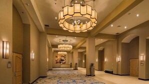 A hotel lobby with a patterned carpet, chandeliers, and a reception desk.