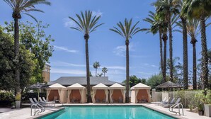 A pool area with lounge chairs and umbrellas, surrounded by palm trees.