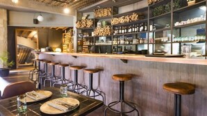 A bar area with stools, shelves with bottles, and a counter.