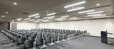 A conference room with rows of chairs, a podium, and a carpeted floor.