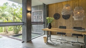 A modern meeting room with a wooden table, black chairs, and a potted plant.