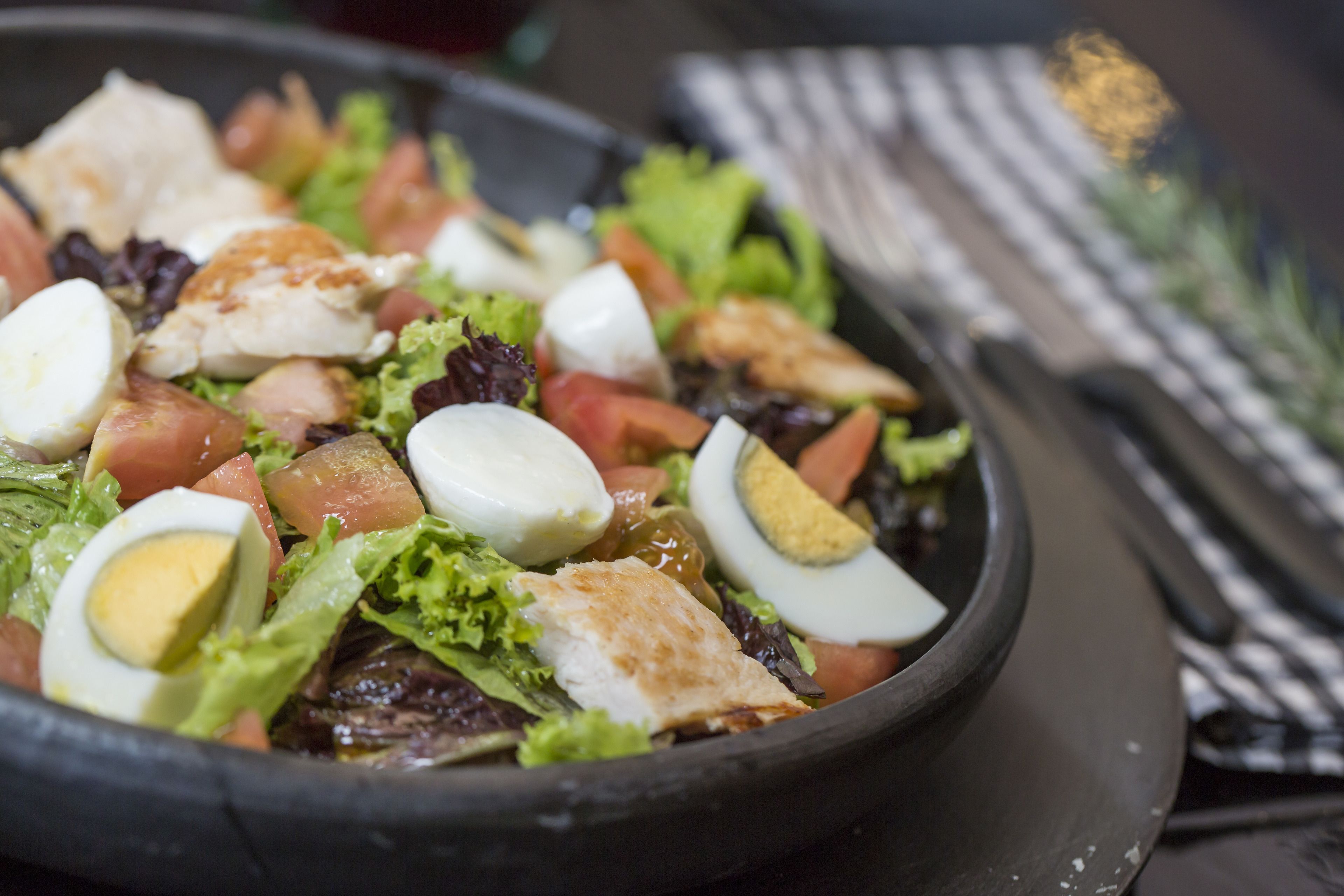 A salad with various ingredients including lettuce, tomatoes, and hard-boiled eggs in a bowl.