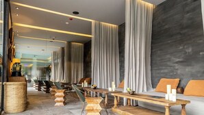 A modern hotel lobby with a long reception desk, seating area, and a large window.