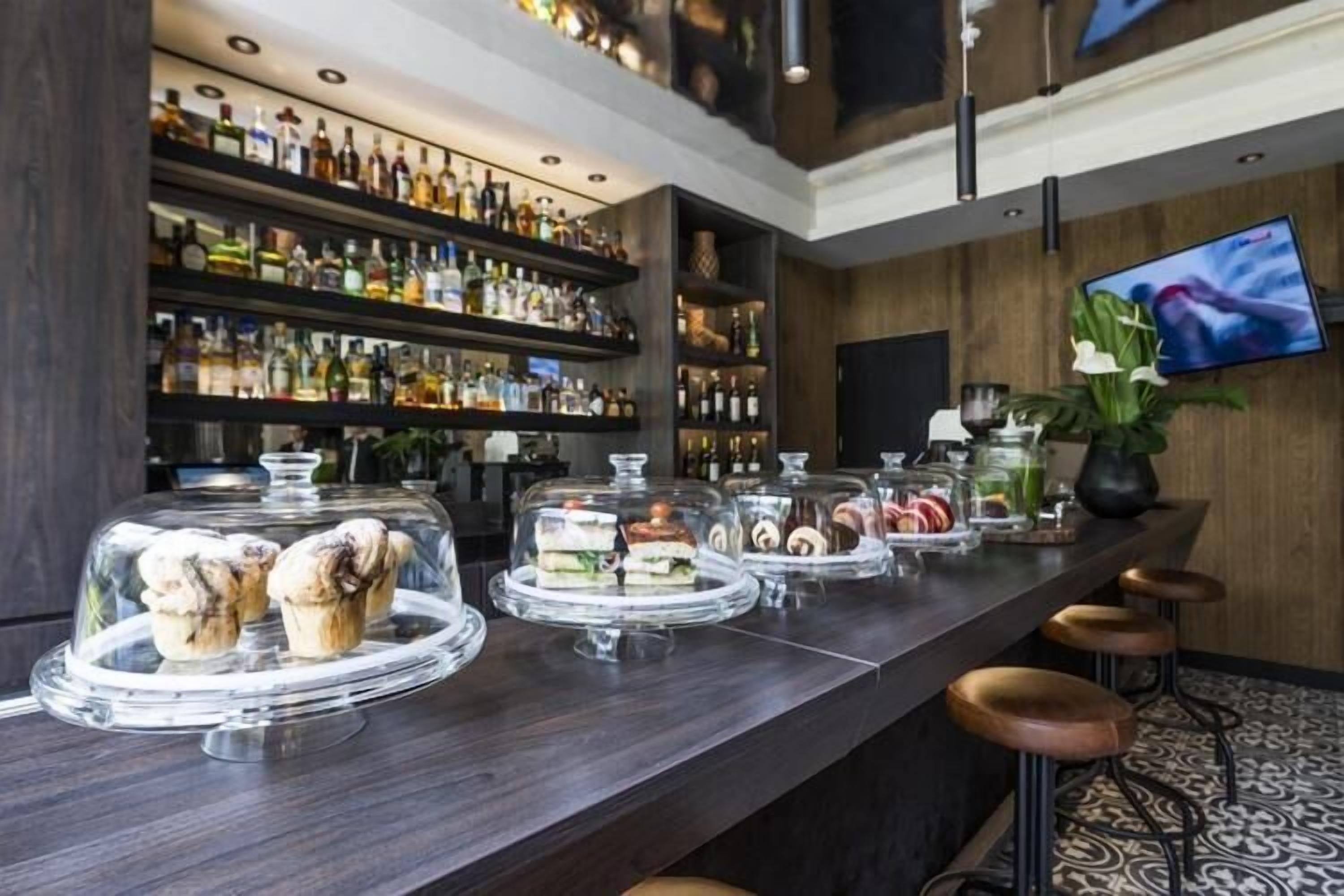 A bar area with shelves of liquor bottles, a TV screen, and a counter with food displays.