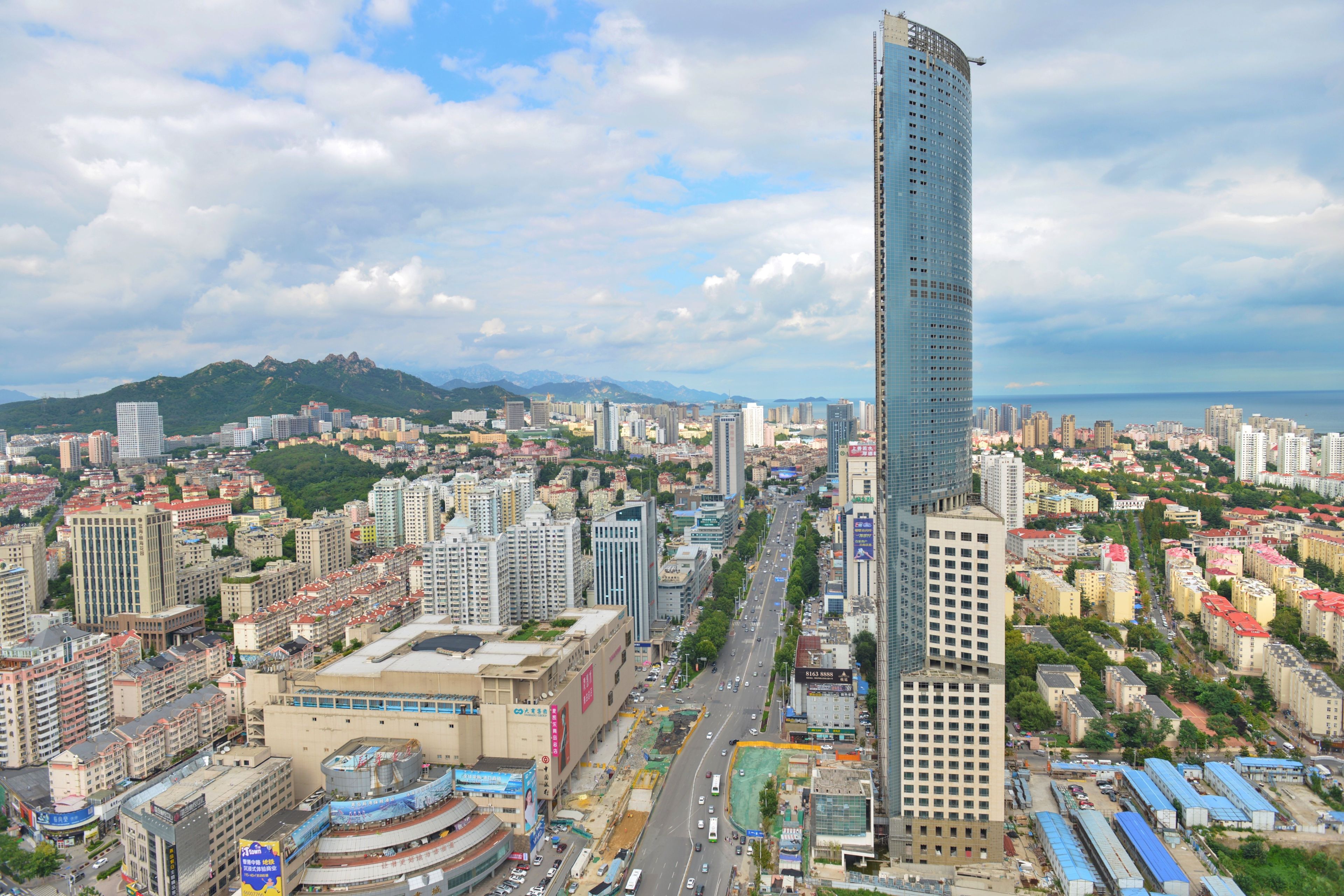 A cityscape with a prominent skyscraper, various buildings, and a mountainous backdrop.
