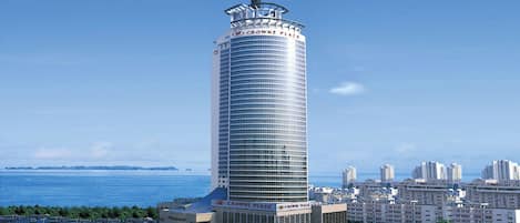 A tall, cylindrical building with a glass facade and a sign reading 'Crowne Plaza' at the top.