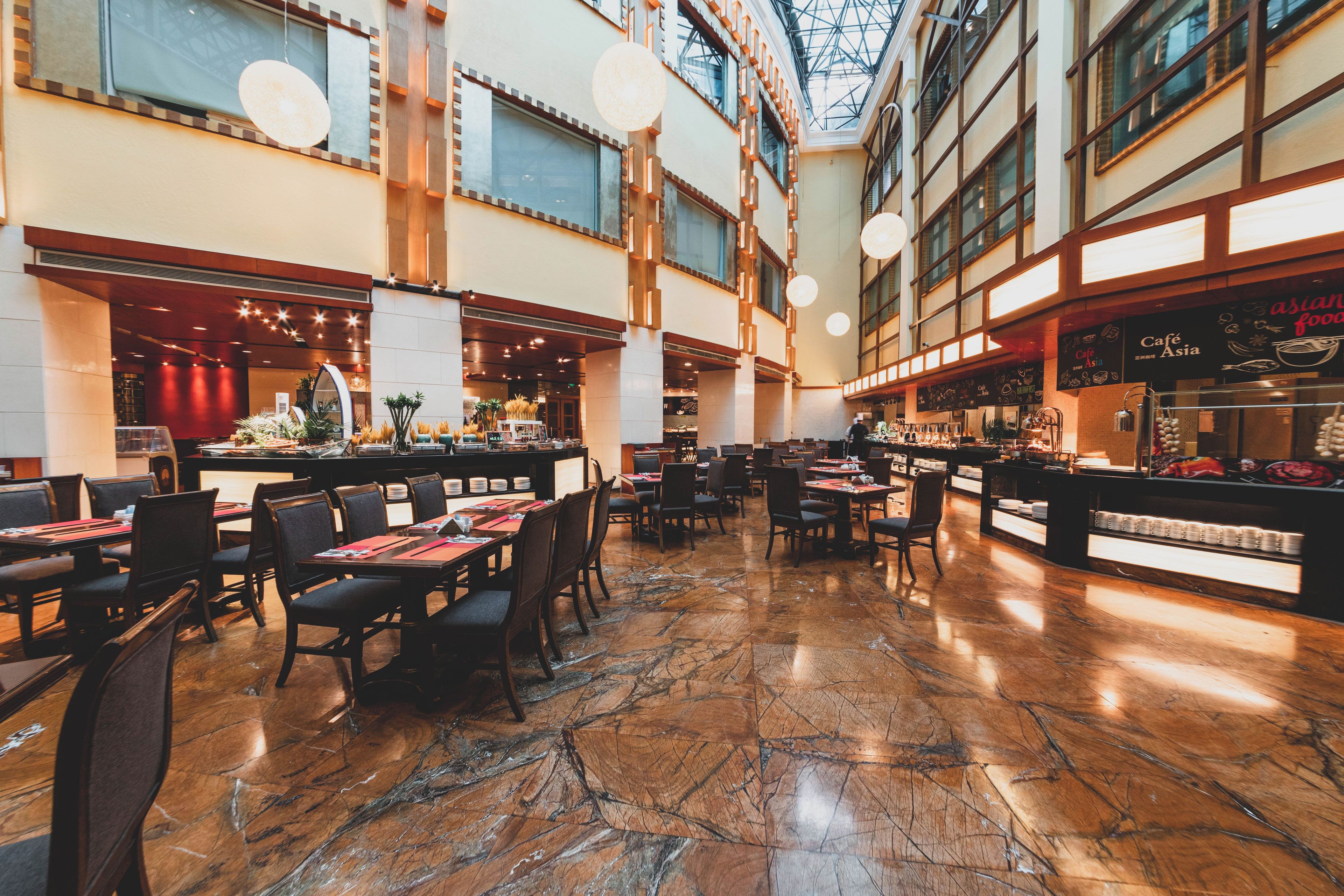 Un'ampia sala ristorante con soffitti alti, pavimento in marmo e diverse zone pranzo.