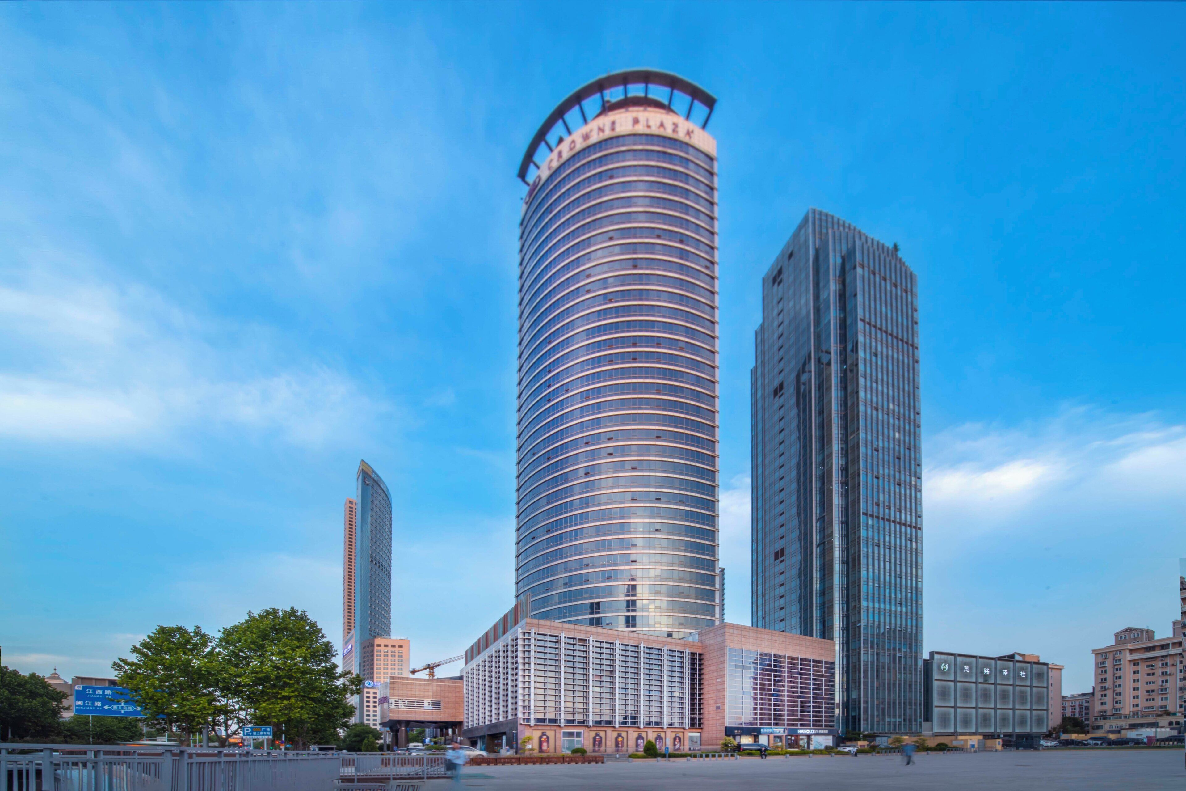 Un moderno edificio de gran altura con fachada curva, rodeado de otros edificios altos y un cielo despejado.