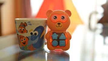 A ceramic mug with a fish design and a bear-shaped toy with buttons.