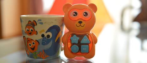 A ceramic mug with a fish design and a bear-shaped toy with buttons.