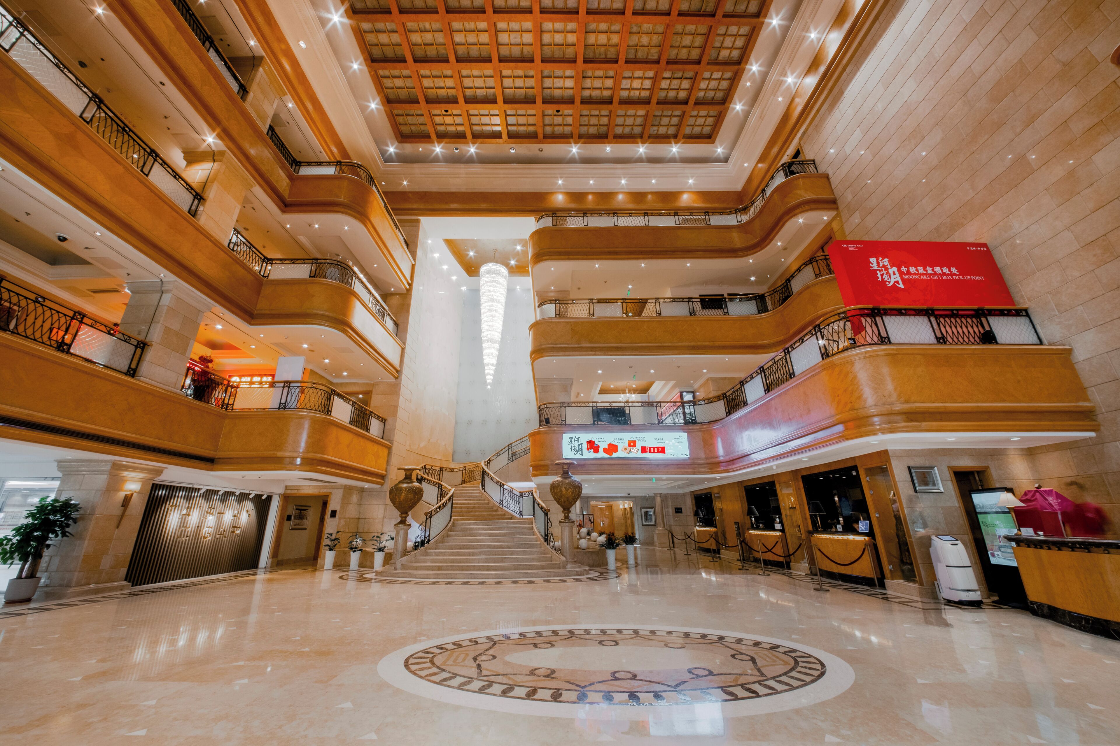 A multi-level atrium with a central staircase, polished marble floors, and a decorative ceiling.