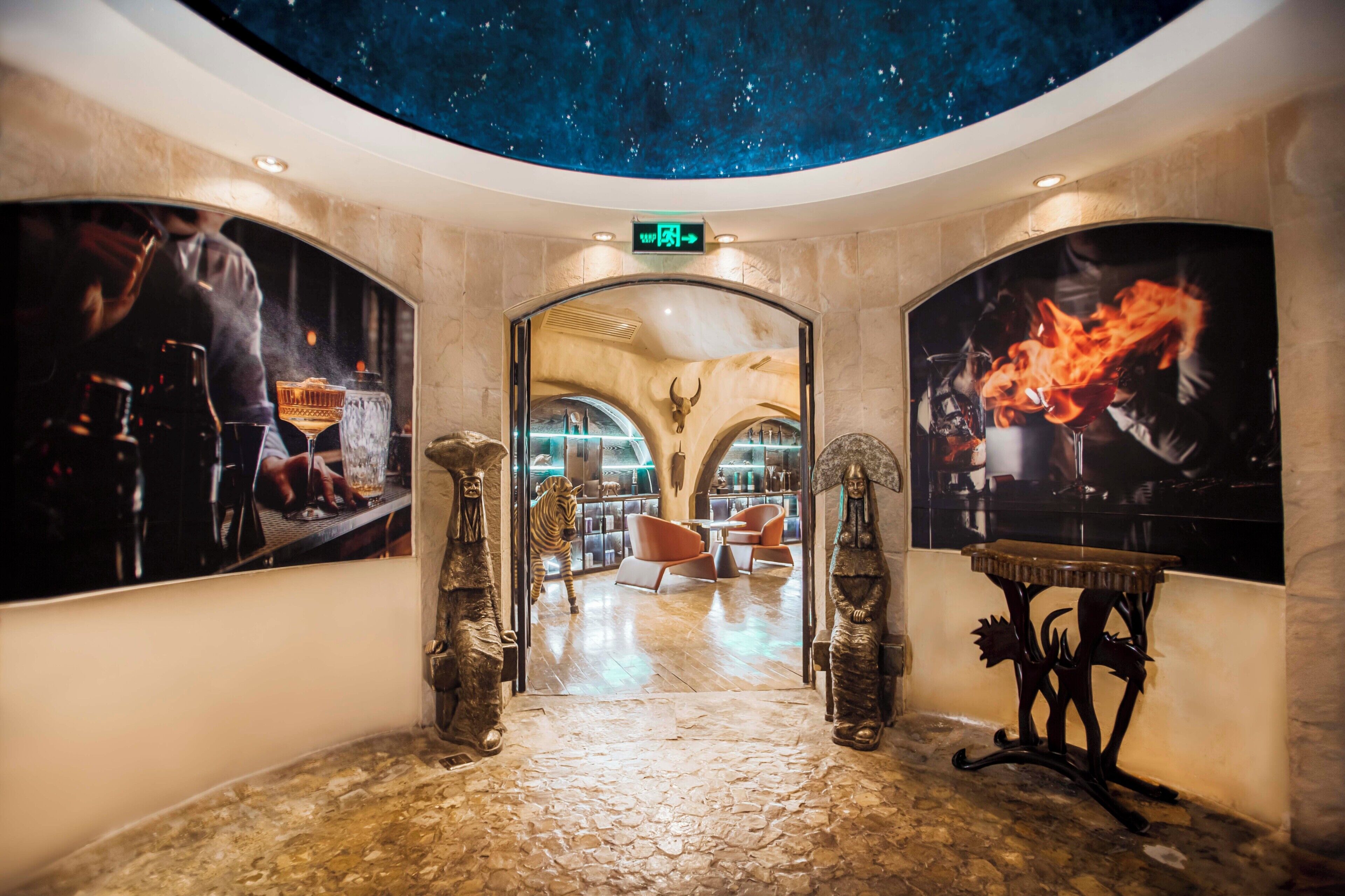 A lobby with a starry ceiling, a zebra statue, and a fire painting.