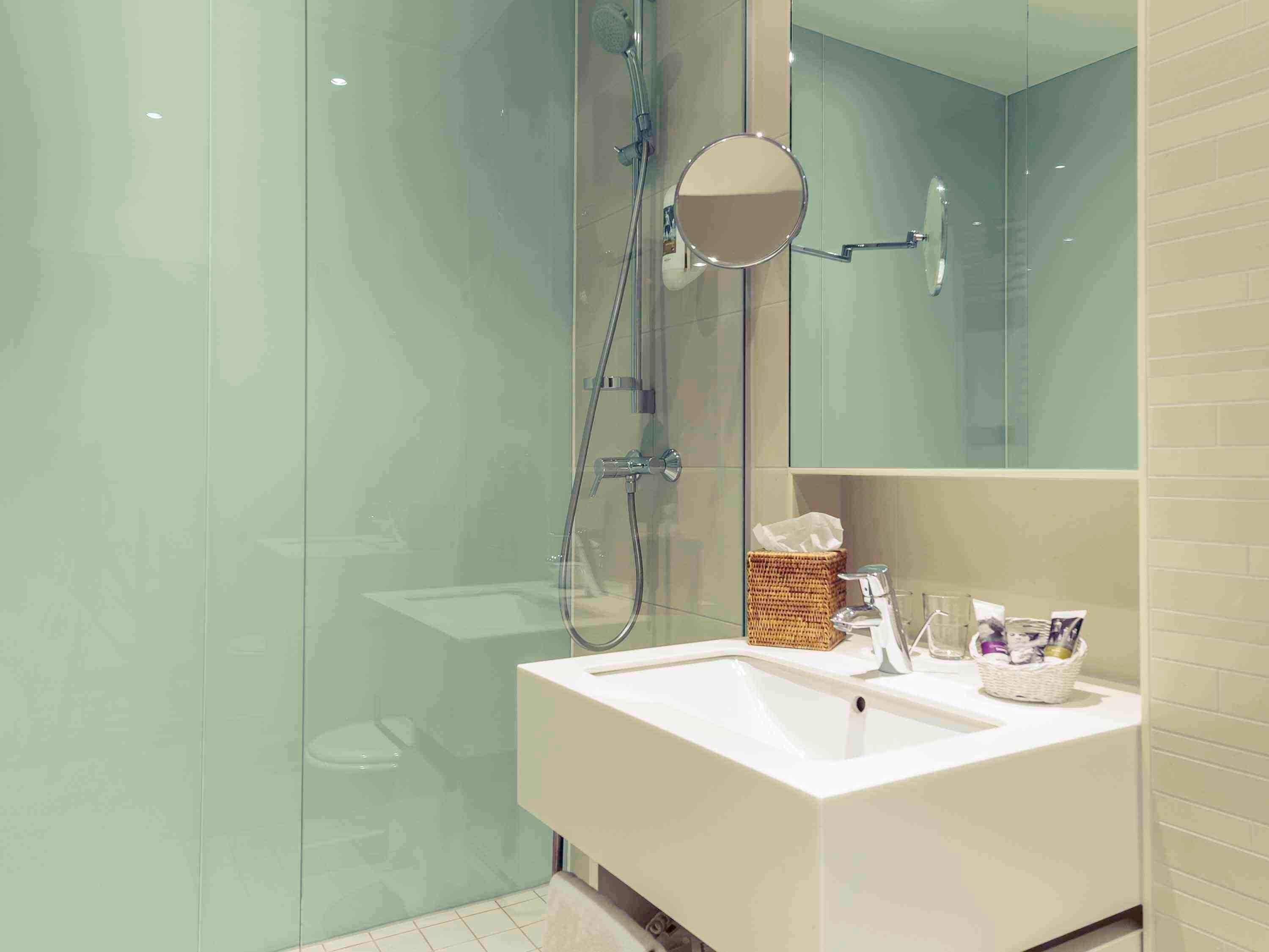 Un baño moderno con cabina de ducha de vidrio, lavabo blanco y espejo.