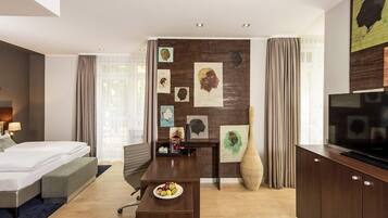 Ein modernes Hotelzimmer mit Bett, Schreibtisch, Fernseher, Wandbild und einem großen Fenster.