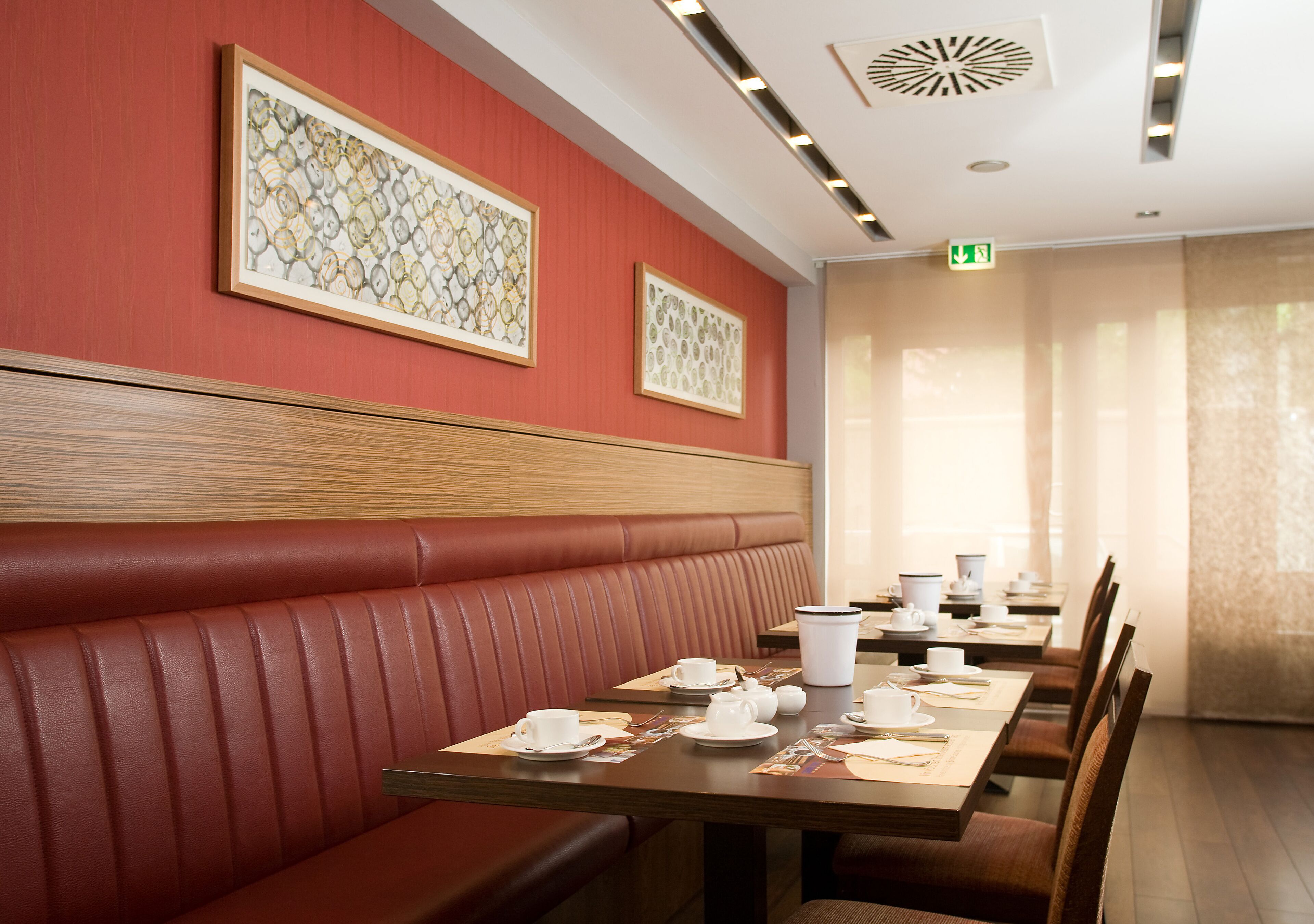 A restaurant with red booths, wooden tables, and framed artwork on the walls.