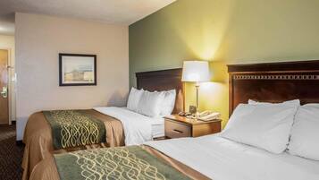 A hotel room with two beds, a nightstand with a lamp, a framed picture on the wall, and a carpeted floor.