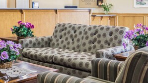 Een hotellobby met een receptiebalie, gestreepte banken en potplanten.