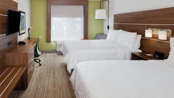 Ein Hotelzimmer mit zwei Betten, einem Fernseher, einem Schreibtisch und einem Fenster mit Jalousien.