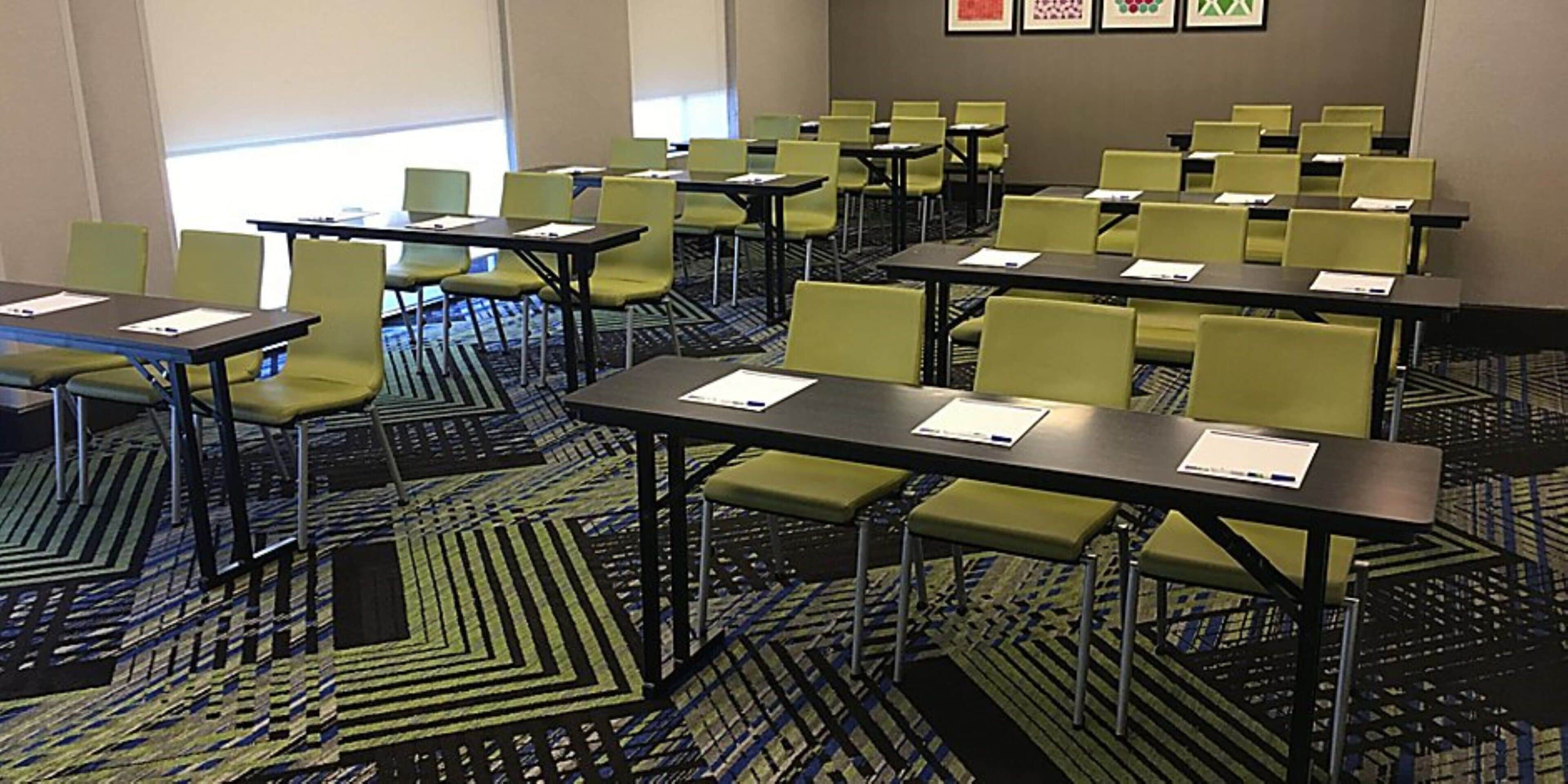 A conference room with tables and chairs, carpeted floor, and a window.