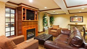 A living room with a fireplace, leather sofas, and a television.