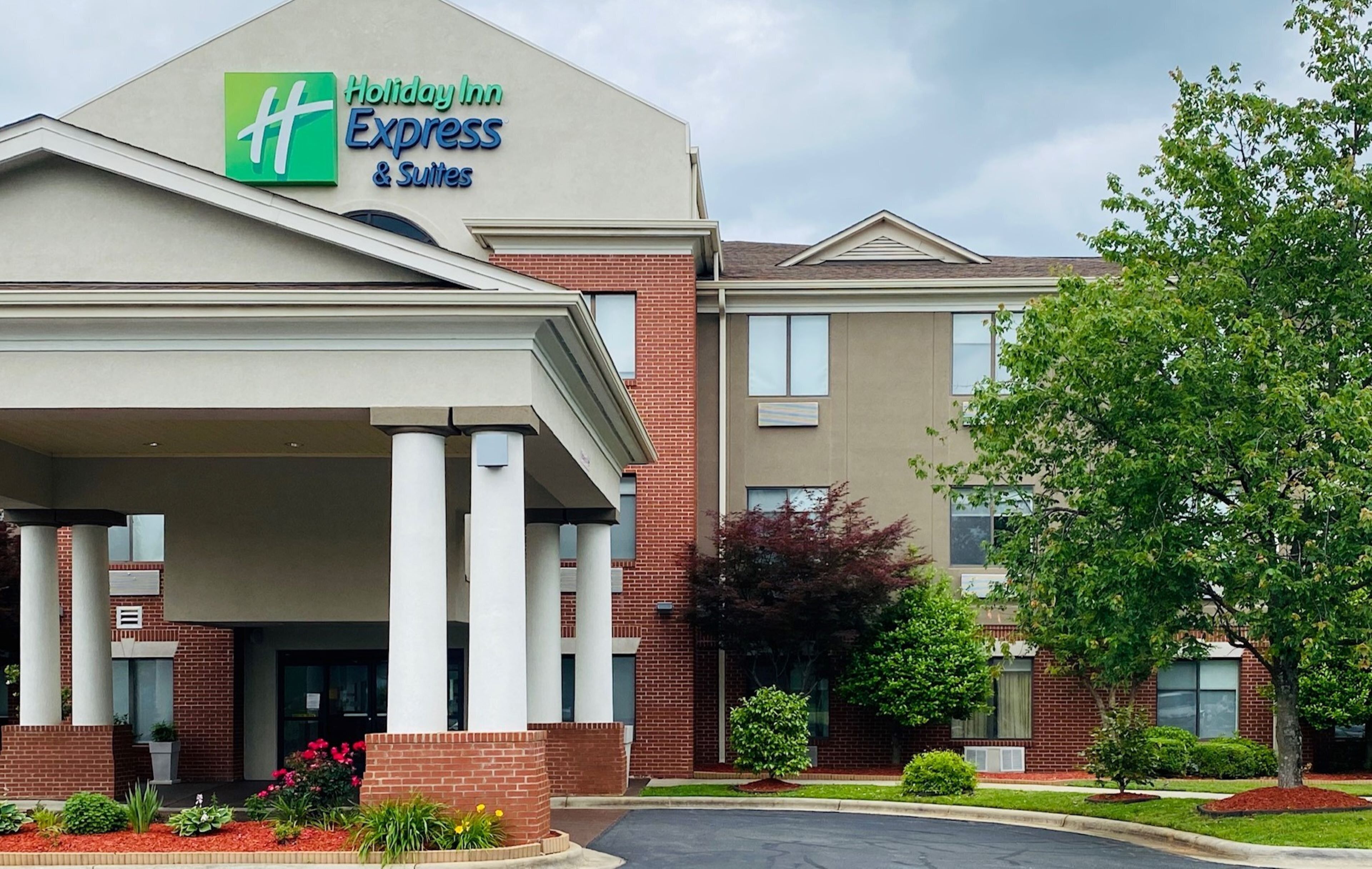 Een Holiday Inn Express & Suites gebouw met een bakstenen gevel, grote kolommen en een overdekte entree.