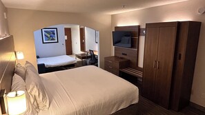 A hotel room with a bed, a desk, a chair, a television, and a wardrobe.