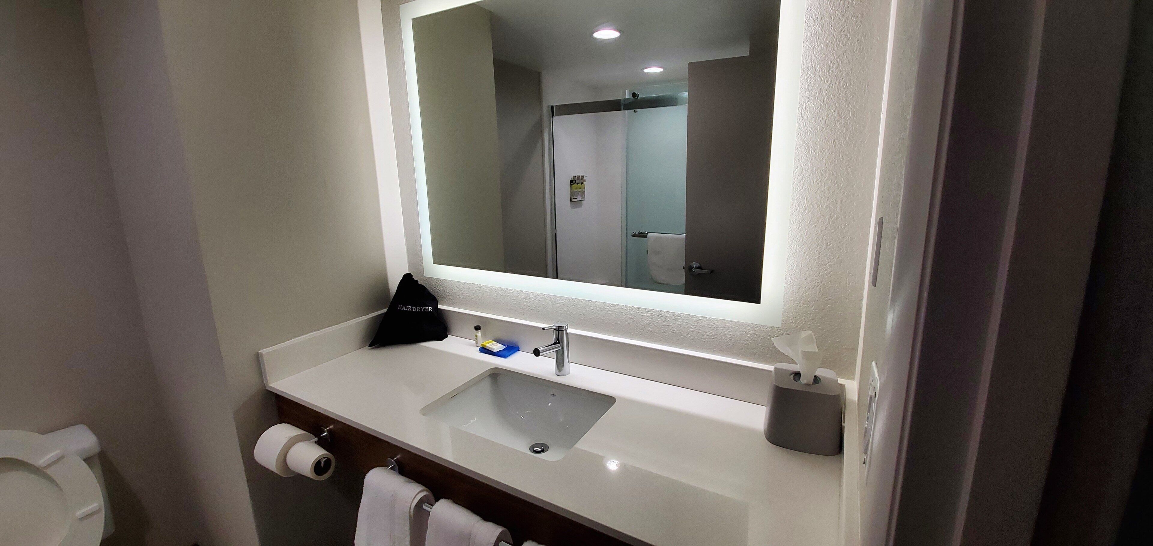 A bathroom with a white sink, a mirror, a towel, and a hairdryer.