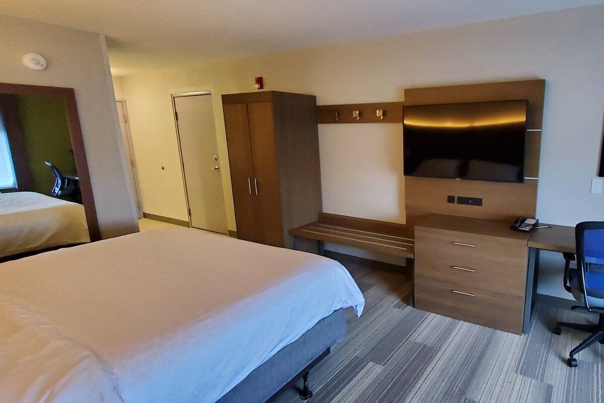 Ein Hotelzimmer mit Bett, Schreibtisch mit Stuhl, Kleiderschrank und Fernseher.
