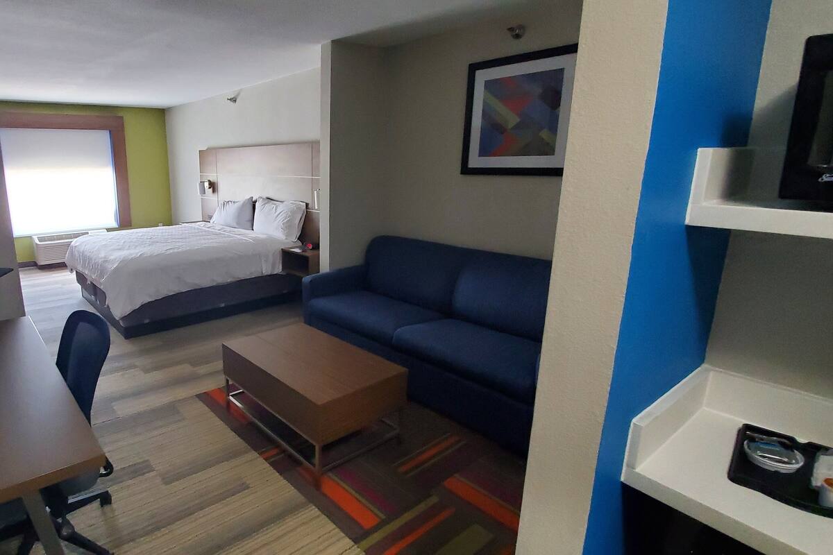 Ein Hotelzimmer mit einem Bett, einem Schreibtisch, einer blauen Couch und einem Fernseher.