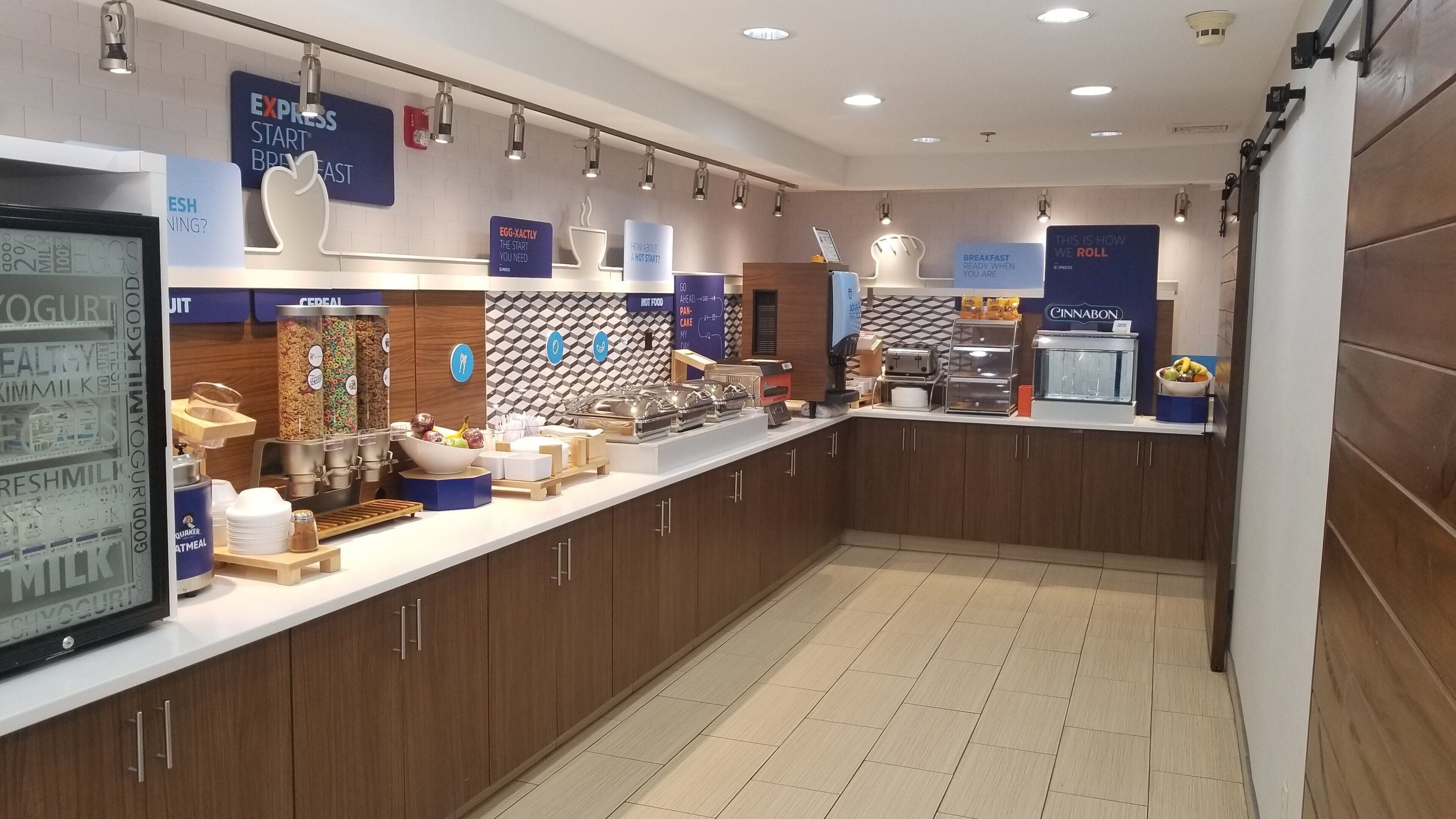 A breakfast buffet area with various food options and a self-service station.