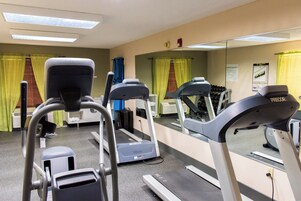 Un gimnasio con cintas de correr, un espejo grande y equipo de ejercicio.