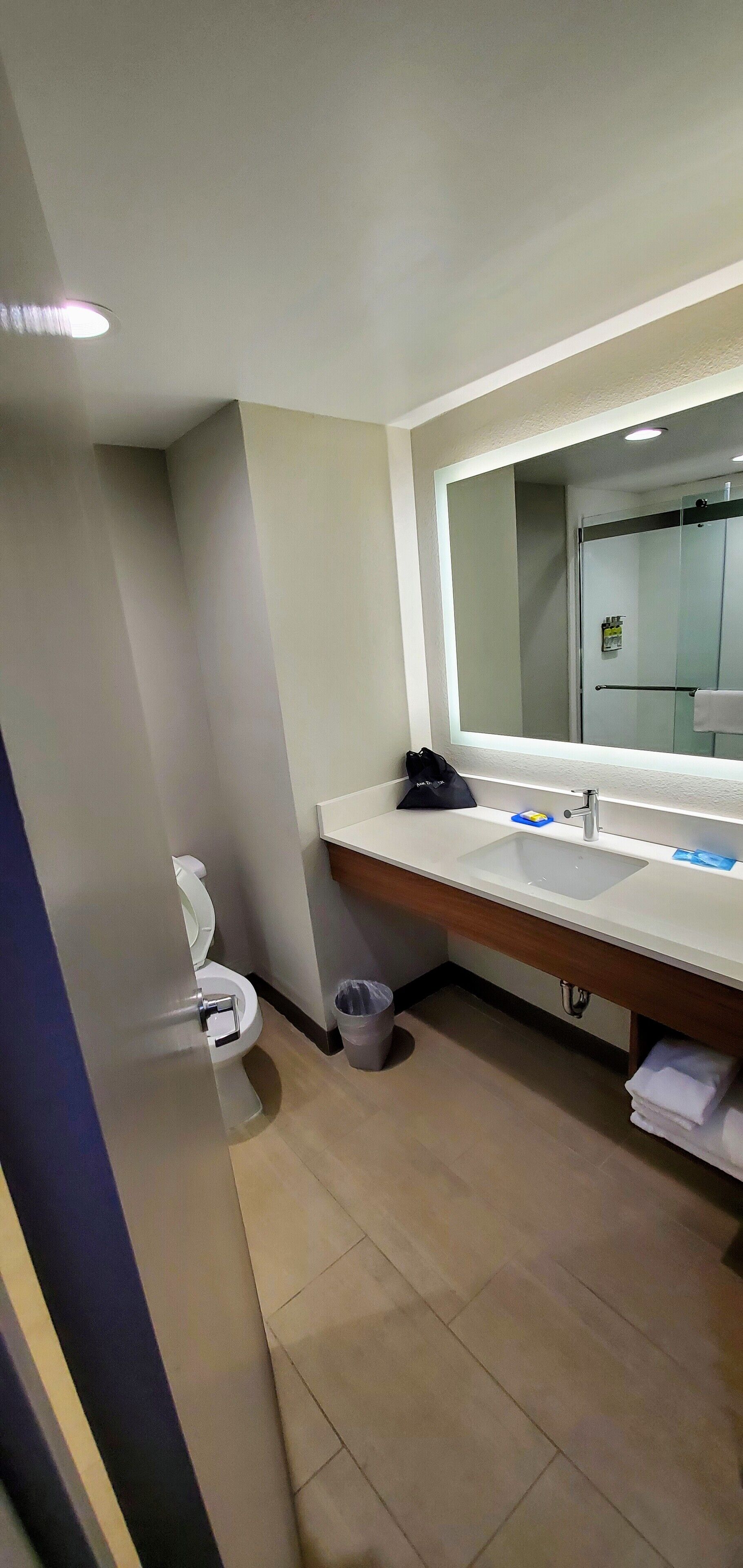 A modern bathroom with a white sink, a large mirror, and a glass shower enclosure.