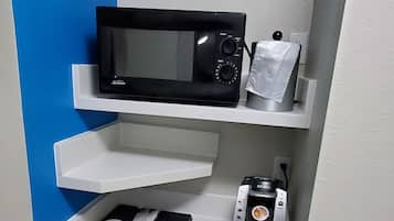 A compact kitchenette with a microwave, coffee machine, and a mini-fridge.