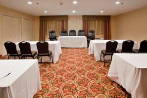 A conference room with a carpeted floor, white tables, and black chairs.