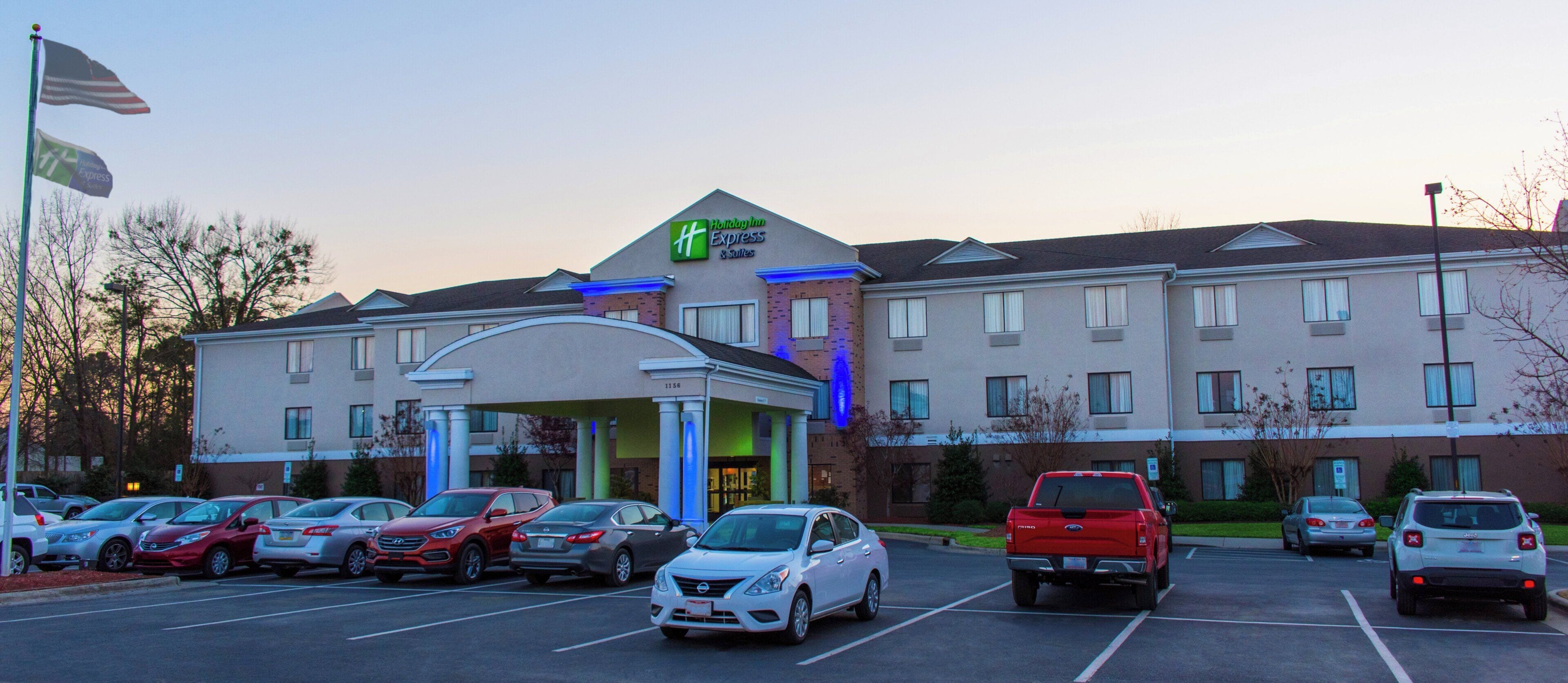 Un hotel Holiday Inn Express con un estacionamiento lleno de coches.