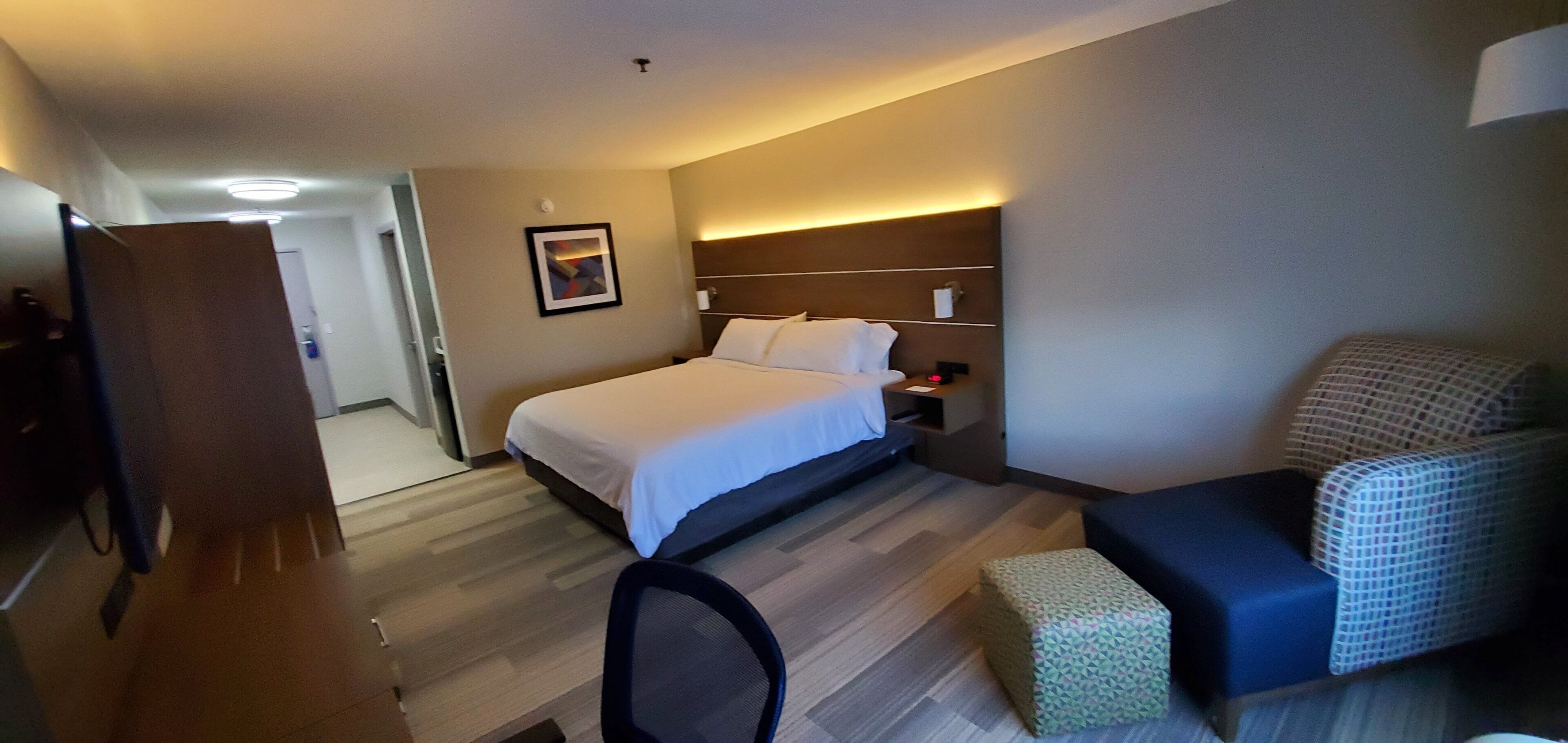 Una habitación de hotel con cama, escritorio, silla y un pequeño rincón de descanso.
